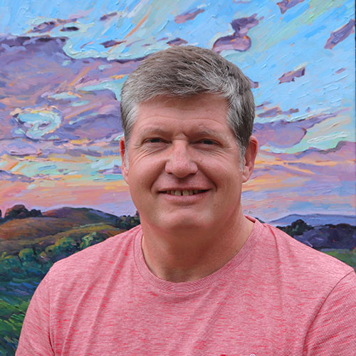 Photograph of James Matheson, fine artist in Jersey, he stands in front of one of his oil paintings. Learn more about James.